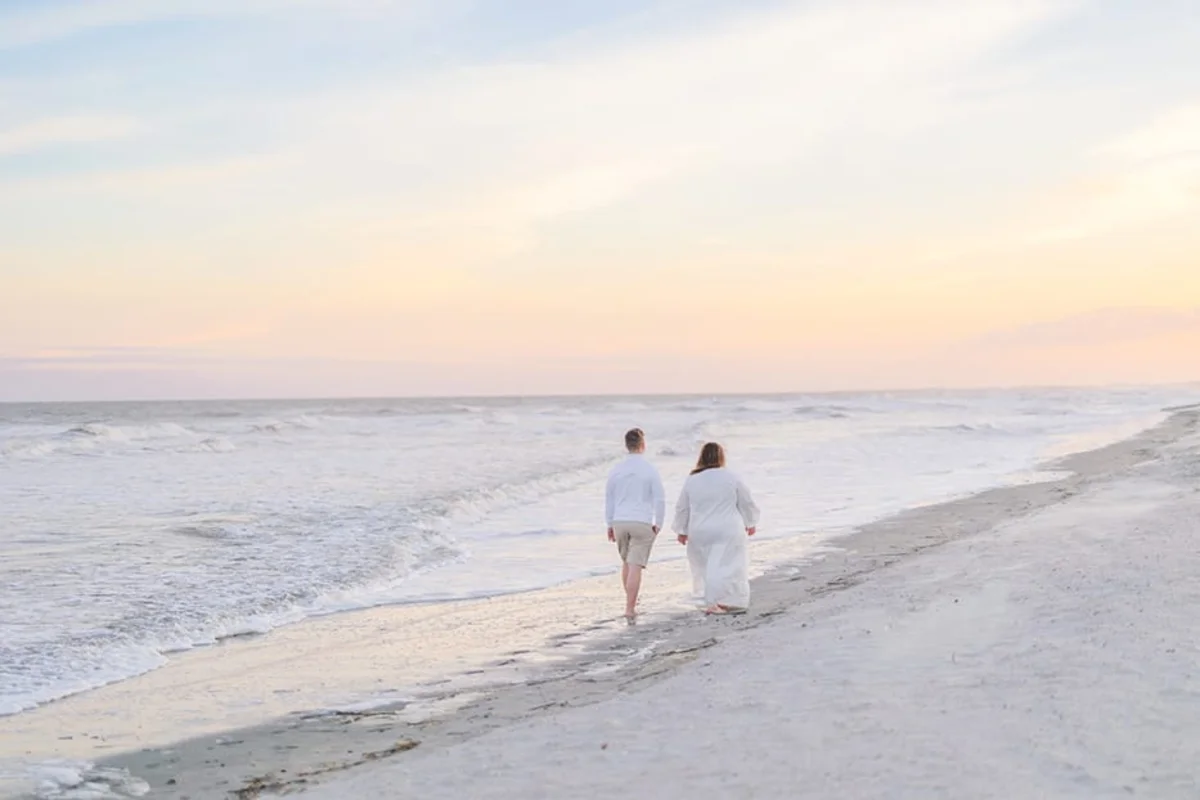 Two people walking on the beach at sunrise, quality time with an adult child